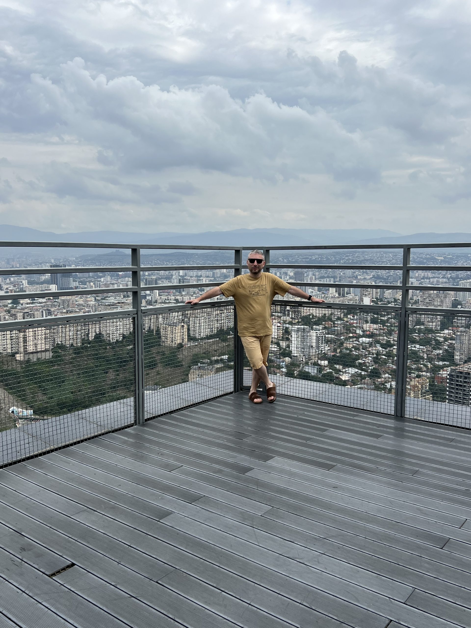 Автор статьи в жёлтой футболке на открытой террасе Axis Towers